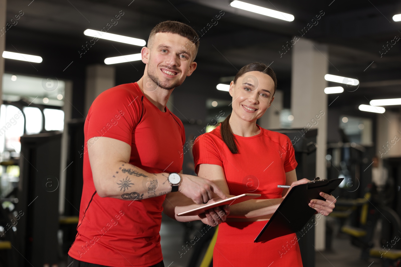 Photo of Personal trainers with tablet and clipboard in gym