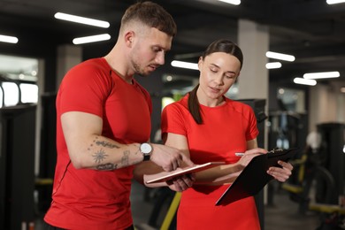 Photo of Personal trainers with tablet and clipboard in gym