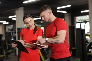 Photo of Personal trainers with tablet and clipboard in gym