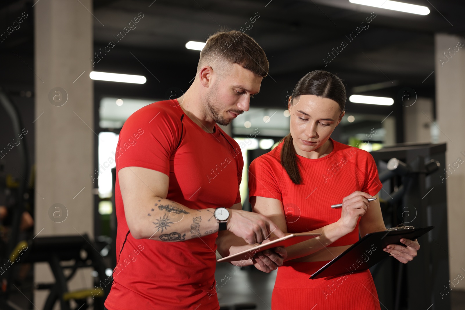 Photo of Personal trainers with tablet and clipboard in gym