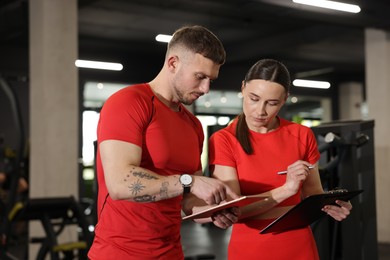 Photo of Personal trainers with tablet and clipboard in gym