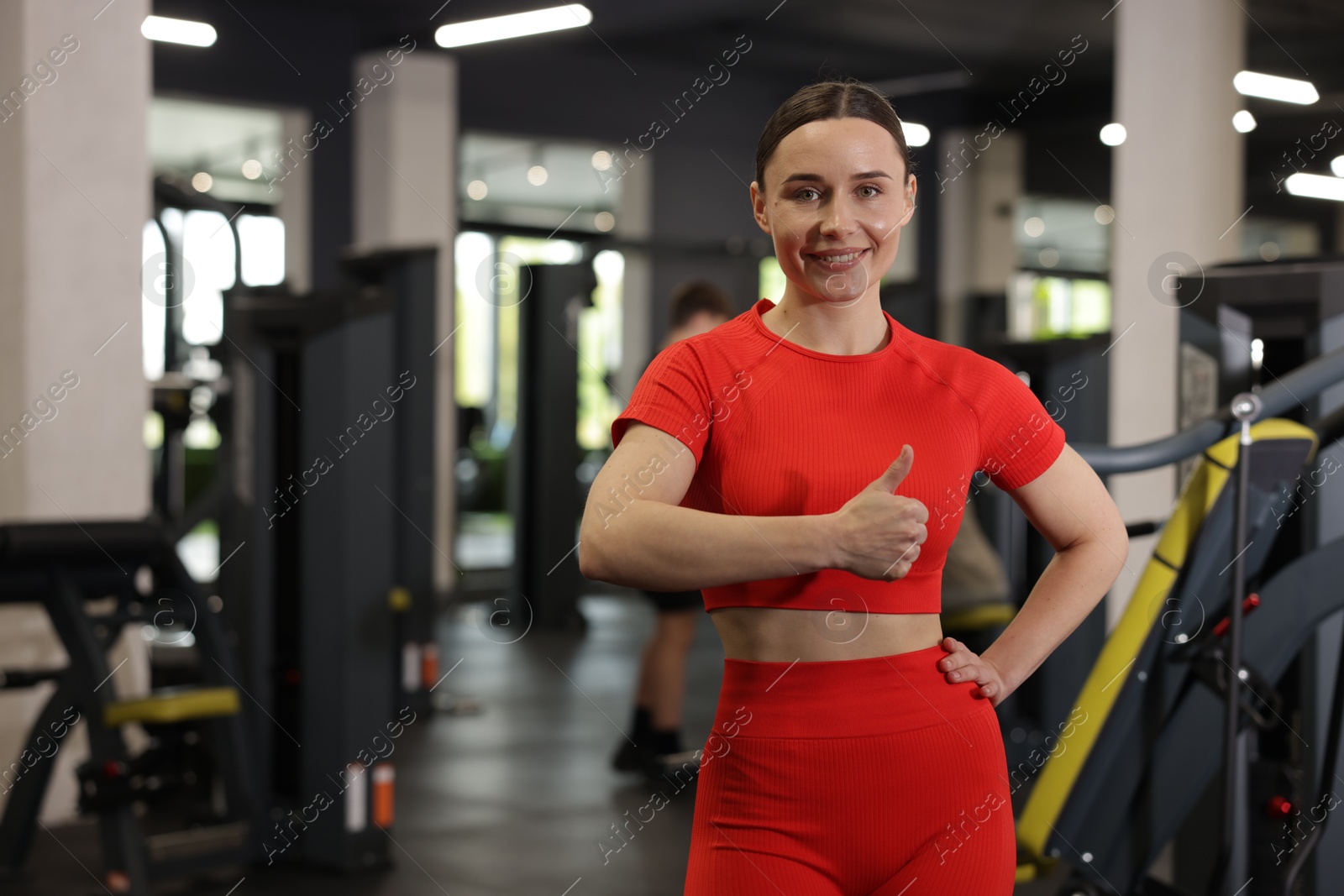 Photo of Personal trainer showing thumbs up in gym. Space for text