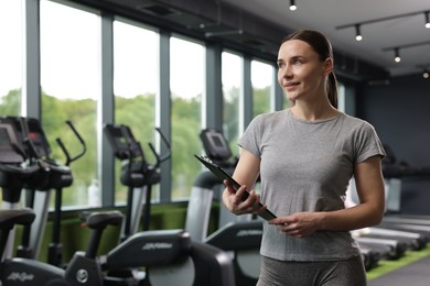 Photo of Professional personal trainer with clipboard in gym. Space for text
