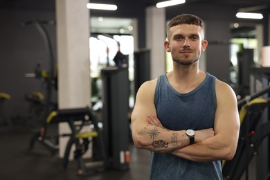 Photo of Portrait of professional personal trainer in gym. Space for text