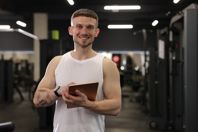 Photo of Personal trainer with tablet in sport center. Space for text