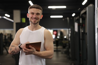 Photo of Personal trainer with tablet in sport center. Space for text