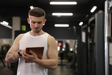 Photo of Personal trainer with tablet in sport center. Space for text