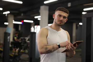 Photo of Personal trainer with tablet in sport center. Space for text