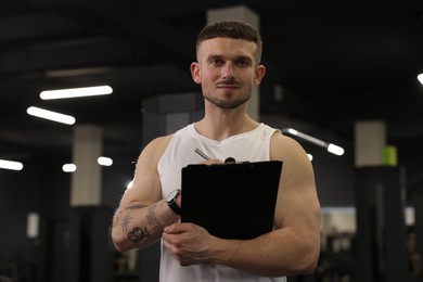 Photo of Personal trainer with clipboard in sport center