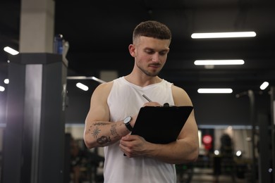 Photo of Personal trainer with clipboard in sport center