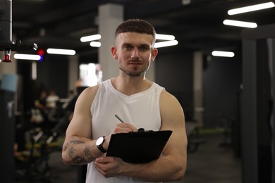 Photo of Personal trainer with clipboard in sport center