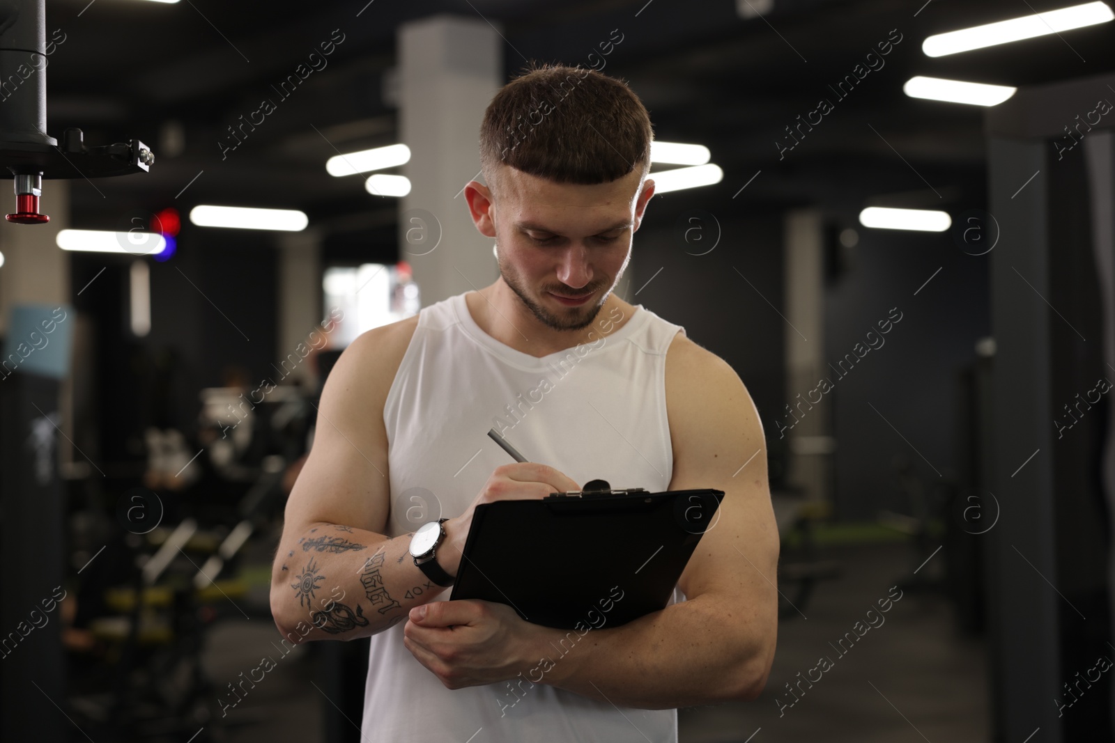 Personal trainer with clipboard in sport center Photo of Personal trainer with clipboard in sport center