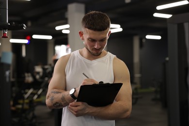 Photo of Personal trainer with clipboard in sport center