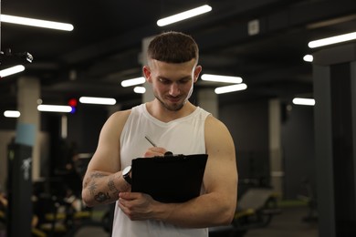 Photo of Personal trainer with clipboard in sport center