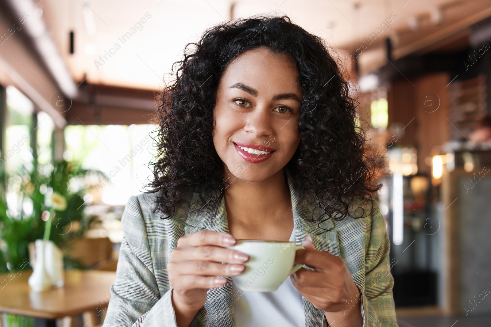 Portrait of smiling Latin American woman drinking coffee in cafe Photo of Portrait of smiling Latin American woman drinking coffee in cafe