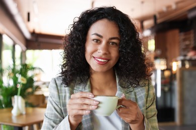 Photo of Portrait of smiling Latin American woman drinking coffee in cafe