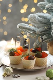 Photo of Tasty canapes and festive decor on white table against blurred lights, closeup. Bokeh effect