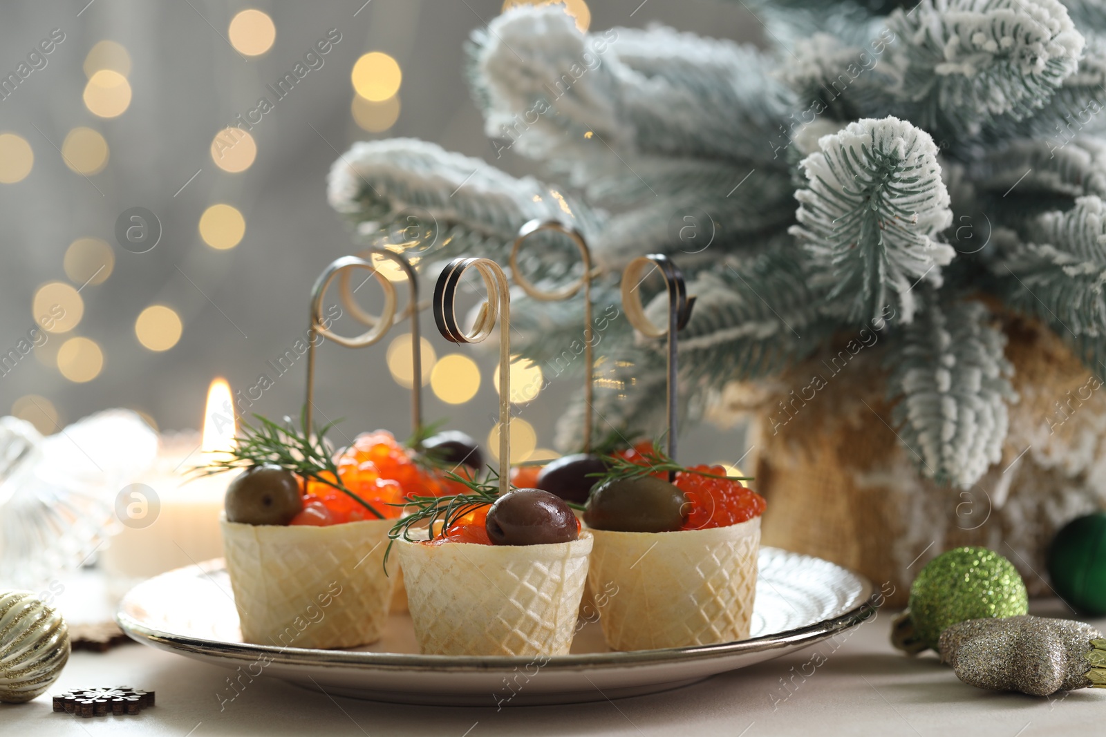 Photo of Tasty canapes and festive decor on white table against blurred lights, closeup. Bokeh effect