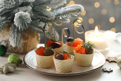 Photo of Tasty canapes and festive decor on white table against blurred lights, closeup. Bokeh effect
