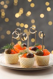 Photo of Tasty canapes on white table against blurred lights, closeup