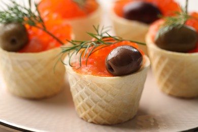 Photo of Tasty canapes with salmon and olives on plate, closeup