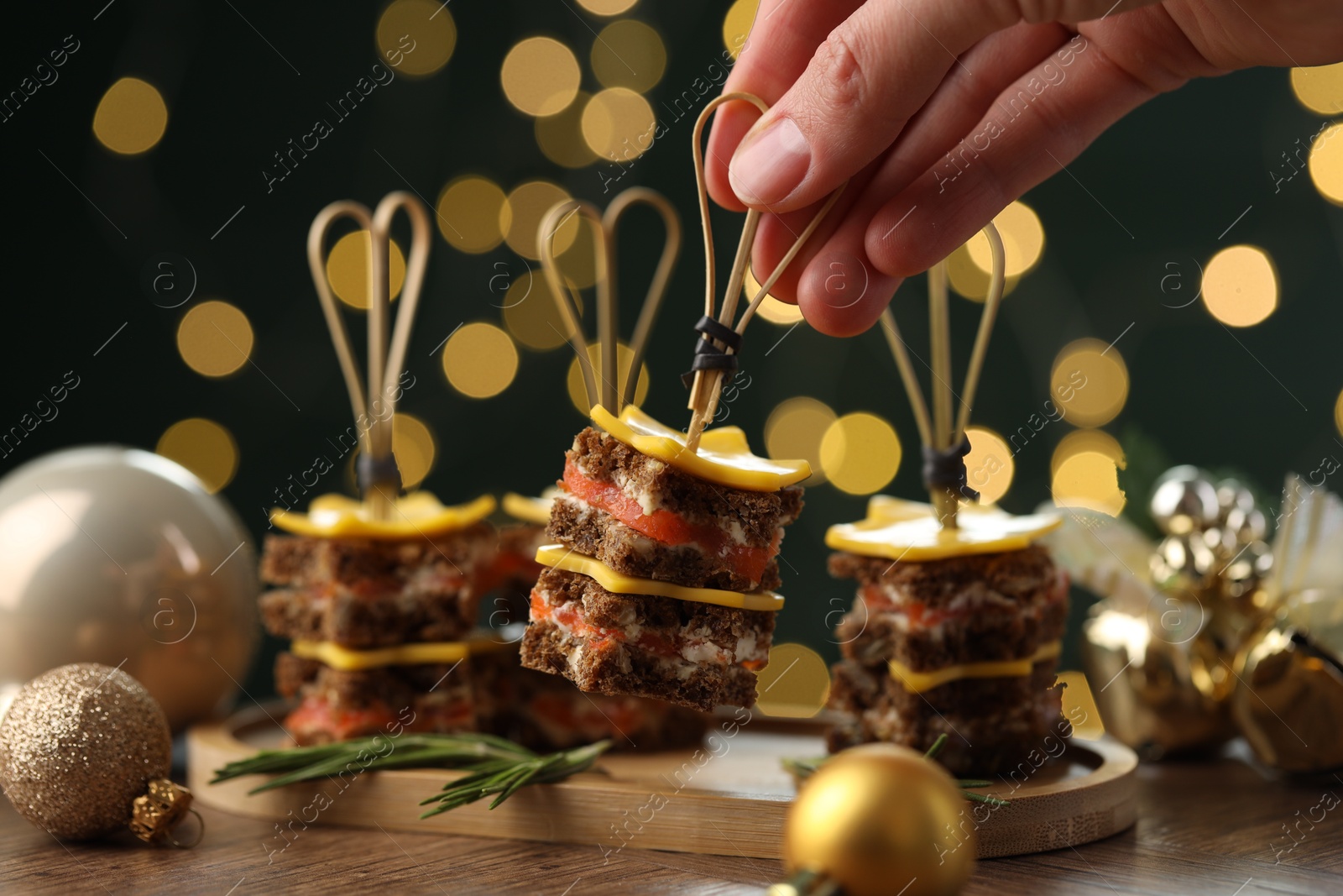 Photo of Tasty canapes with cheese on wooden table against blurred lights, closeup. Bokeh effect