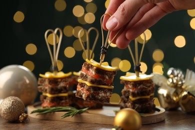 Photo of Tasty canapes with cheese on wooden table against blurred lights, closeup. Bokeh effect