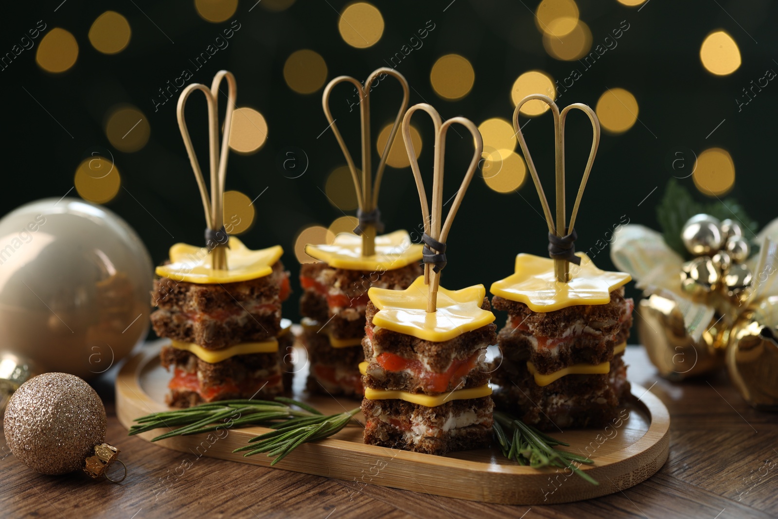 Photo of Tasty canapes with cheese on wooden table against blurred lights, closeup. Bokeh effect