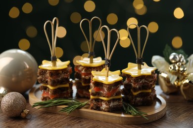 Photo of Tasty canapes with cheese on wooden table against blurred lights, closeup. Bokeh effect