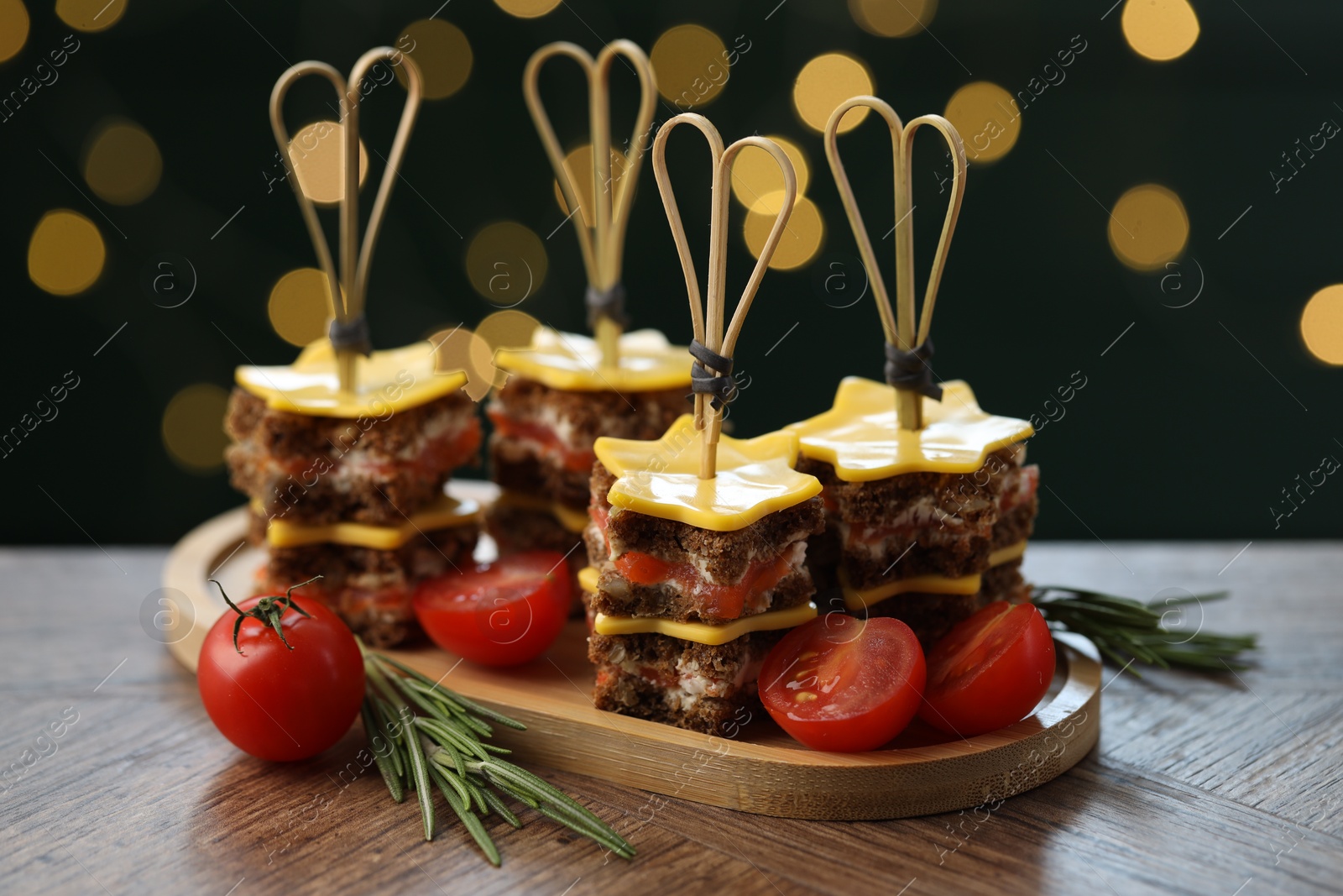 Photo of Tasty canapes with cheese on wooden table against blurred lights, closeup. Bokeh effect