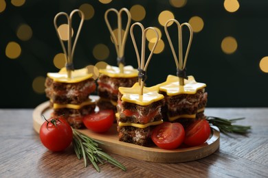 Photo of Tasty canapes with cheese on wooden table against blurred lights, closeup. Bokeh effect