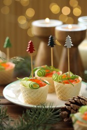 Photo of Tasty canapes and festive decor on wooden table against blurred lights, closeup. Bokeh effect