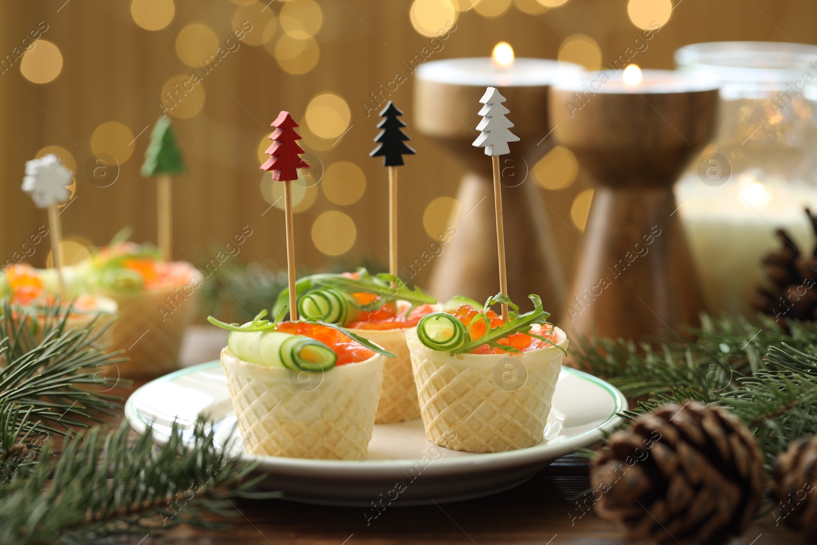 Photo of Tasty canapes and festive decor on wooden table against blurred lights, closeup. Bokeh effect