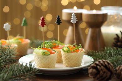 Photo of Tasty canapes and festive decor on wooden table against blurred lights, closeup. Bokeh effect