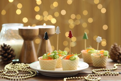 Photo of Tasty canapes and festive decor on wooden table against blurred lights, closeup. Bokeh effect