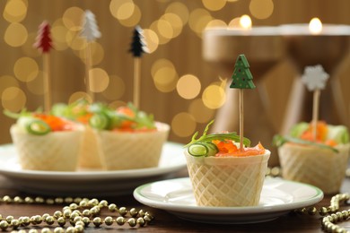 Photo of Tasty canapes and festive decor on wooden table against blurred lights, closeup. Bokeh effect