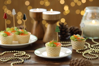 Photo of Tasty canapes and festive decor on wooden table against blurred lights, closeup. Bokeh effect
