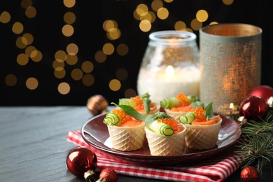 Photo of Tasty canapes and festive decor on black table against blurred lights, closeup. Bokeh effect