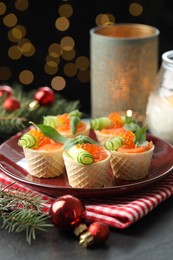 Photo of Tasty canapes and festive decor on black table against blurred lights, closeup. Bokeh effect