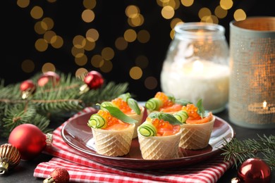 Photo of Tasty canapes and festive decor on black table against blurred lights, closeup. Bokeh effect