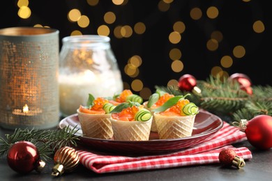 Photo of Tasty canapes and festive decor on black table against blurred lights, closeup. Bokeh effect
