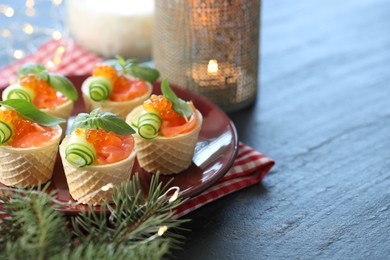 Photo of Tasty canapes and fir tree branches on blue wooden table, closeup. Space for text