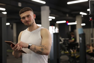 Photo of Personal trainer with tablet in sport center. Space for text
