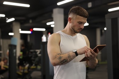 Photo of Personal trainer with tablet in sport center. Space for text