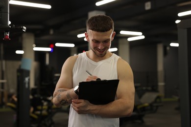 Photo of Personal trainer with clipboard in sport center