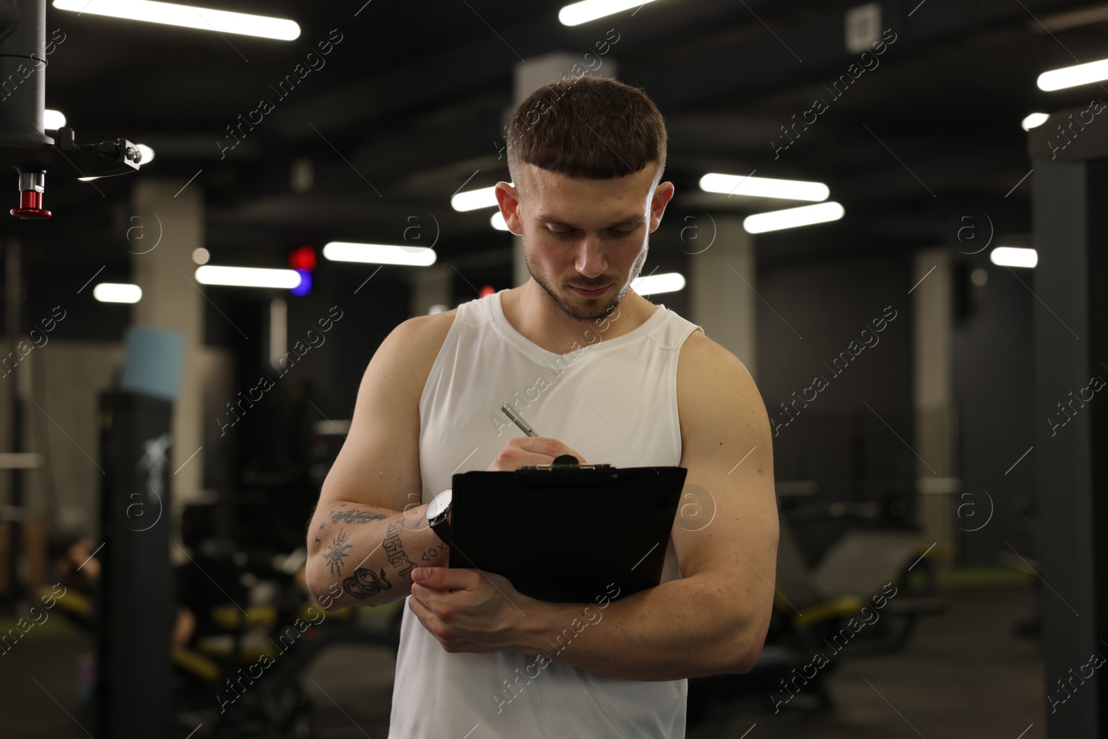 Personal trainer with clipboard in sport center Photo of Personal trainer with clipboard in sport center