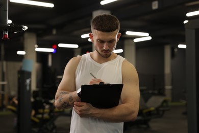 Photo of Personal trainer with clipboard in sport center