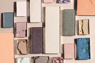 Photo of Beautiful eyeshadow refill pans on beige background, flat lay