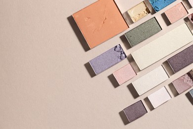 Photo of Beautiful eyeshadow refill pans on beige background, flat lay. Space for text