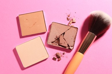 Photo of Refill pans of cosmetic products and brush on pink background, flat lay